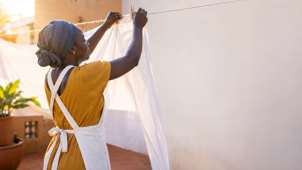 Une laveuse Washed étend du linge blanc au soleil, sur une terrasse à Lomé.